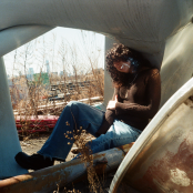 Artist Jane Remover sitting in a Junk Yard smoking a cigarette
